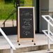 An Aarco oak A-Frame chalkboard sign with writing and a drawing of vegetables.