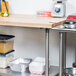 A wood top work table with a stainless steel base and undershelf in a professional kitchen.