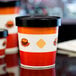 A red and white striped paper soup cup with a vented lid.