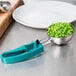 A teal Vollrath Jacob's Pride #5 disher with peas in a plate.