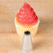 A cupcake with pink frosting on top with an Ateco French star piping tip nozzle.
