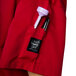 The pocket of a tomato red Chef Revival chef jacket with a pen and a bottle inside.