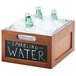 A Cal-Mil bamboo-colored wood chalkboard ice housing with bottles of water in it.