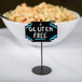 A black Cal-Mil sign holder on a table with a bowl of food.