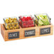 A Cal-Mil wooden box display with 3 glass jars holding limes, cherries, and green olives.