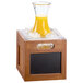 A Cal-Mil bamboo-colored chalkboard ice housing with a glass pitcher of orange juice on ice.