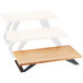 A wooden table with a white rectangular Cal-Mil bamboo stair-step riser on it.