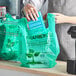 A person putting a blue card in a green EcoChoice plastic bag with a thank you sign.
