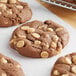 A close up of a chocolate cookie with nuts on top.