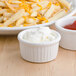 A plate of french fries with Tuxton white bowls of sauces.