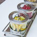 A Cal-Mil stainless steel horizontal display with notched lids holding lemons and limes on a table outdoors.