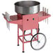 A pink Carnival King cotton candy machine with a large stainless steel bowl on a cart.