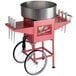 A pink Carnival King cotton candy machine with a silver bowl on a red cart.