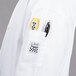 A person wearing a white Chef Revival chef jacket with a pen in the pocket.