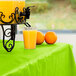 A glass of orange juice on a table with a Fresh Lime Green plastic table cover.