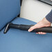A person using a ProTeam vacuum cleaner to vacuum an office chair with a black ProTeam tube.