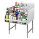 An Advance Tabco stainless steel liquor display rack on a counter with bottles of liquor on it.
