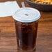 A Cambro clear plastic tumbler with a straw in it on a table with a brown drink.