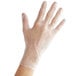 A person's hand wearing a clear plastic Noble Products glove.
