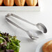 Vollrath stainless steel buffet tongs serving salad on a table.