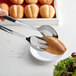 A pair of Vollrath stainless steel buffet tongs holding a loaf of bread over a plate of lettuce.