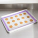 A Mercer Culinary purple silicone baking mat on a baking sheet with cookies.