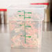 A translucent Cambro polypropylene square food storage container with spiral pasta in it.
