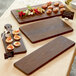 An American Metalcraft ash wood serving board on a table with food.