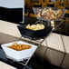An American Metalcraft chrome display stand on a hotel buffet counter with bowls of snacks.