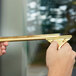A person using a Unger Brass Channel on a window with a gold handle.
