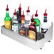 A stainless steel double tier speed rail holding bottles of liquor on a counter.