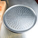 An American Metalcraft heavy weight aluminum pizza pan with perforations and a metal tray with holes on it.