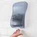 A hand reaches for a San Jamar Rely Arctic Blue touchless foam soap dispenser on a wall.