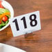 An American Metalcraft rectangular hammered aluminum card holder with a number on a plate next to a bowl of salad.