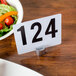 A white plate with a metal American Metalcraft round hammered aluminum card holder with the number 1 on it, holding a salad.