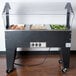 An Advance Tabco stainless steel electric hot food table with three pans of food on an open base.