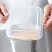 A hand holding a clear plastic container with food inside.