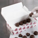 A hand holding a 1 lb. heart-shaped chocolate candy box.