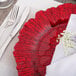 A Charge It by Jay Reef Red Glass Charger Plate with silverware and a napkin on a table.