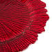 A close up of a red Charge It by Jay glass charger plate with a scalloped edge.