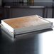 A white rectangular fiberglass sheet pan extender on a metal tray with a loaf of bread inside.