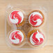 A clear plastic InnoPak container holding four cupcakes with red and white frosting.