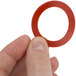 A person holding a red rubber Avantco faucet gasket.