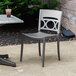 A Grosfillex Moon titanium gray and charcoal stacking chair on an outdoor patio.