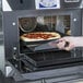 A hand taking a pizza out of a Merrychef eikon e4s rapid cook oven.