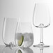 Three Stolzle all-purpose wine glasses with ice and lime slices on the side.