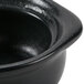 A close up of a black Hall China onion soup bowl.