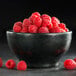 A black Hall China chili bowl filled with raspberries.