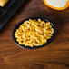 A black Hall China oval baker dish filled with macaroni and cheese on a table.