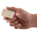 A hand holding a white Dial bar of soap.
